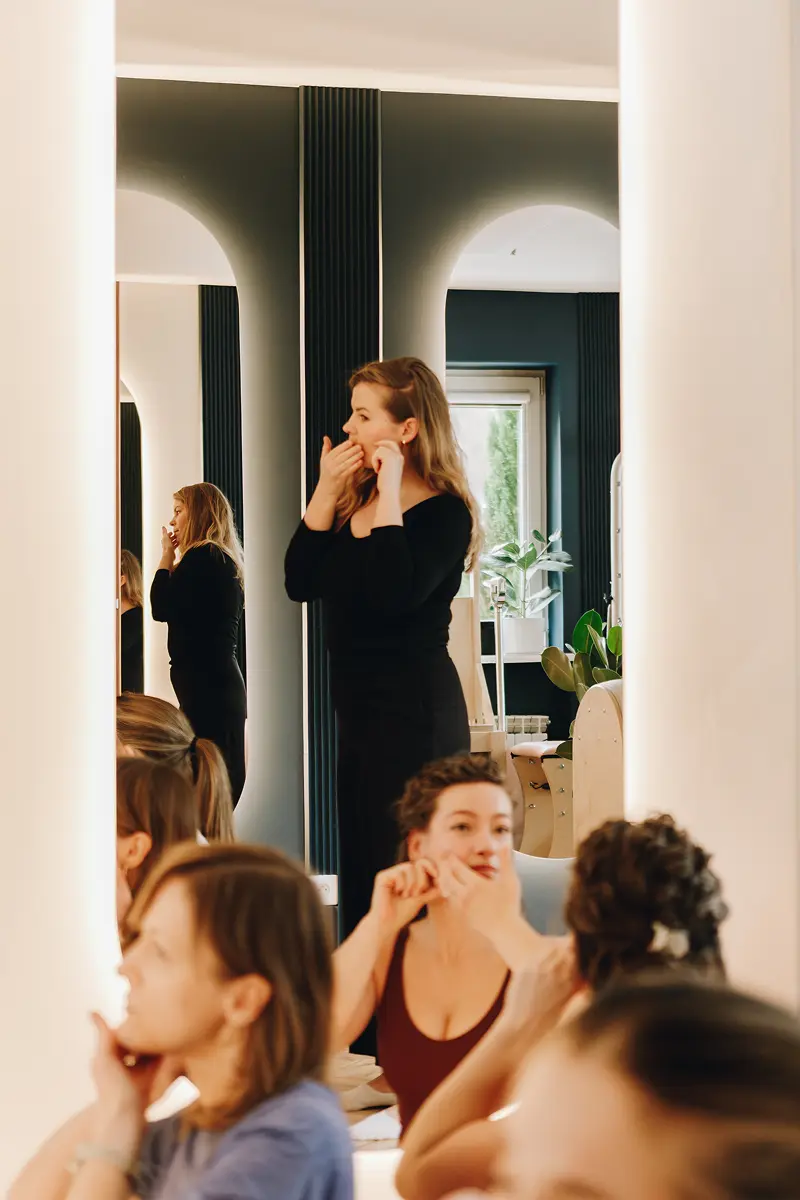 Kobiety podczas masażu twarzy przed podświetlanymi lustrami w eleganckim studiu.