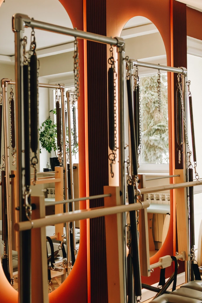 Nowoczesny tower do pilatesu na tle podświetlanych, łukowych luster.